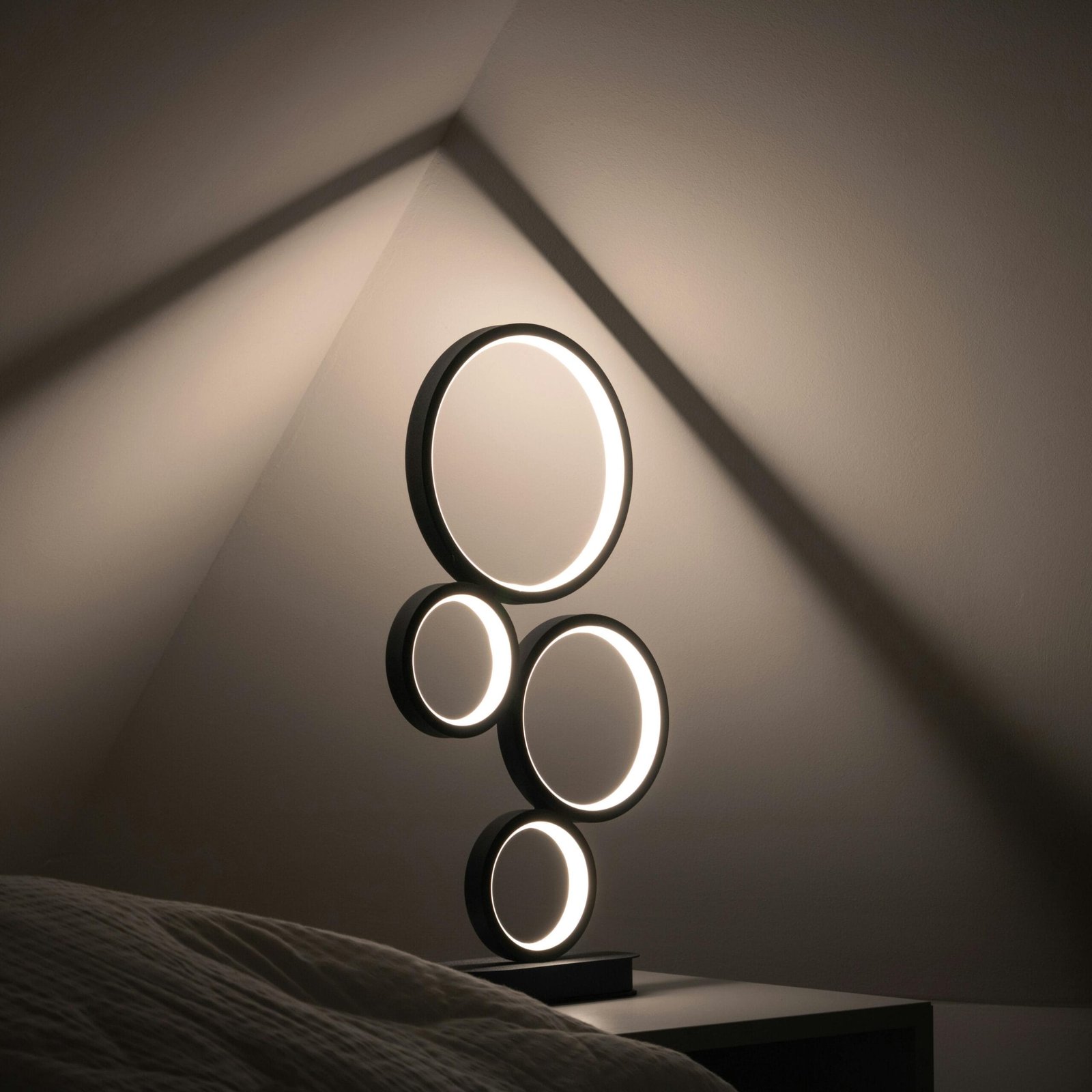 Elegant minimalist lamp with circular design, casting soft light in a dim, modern room.