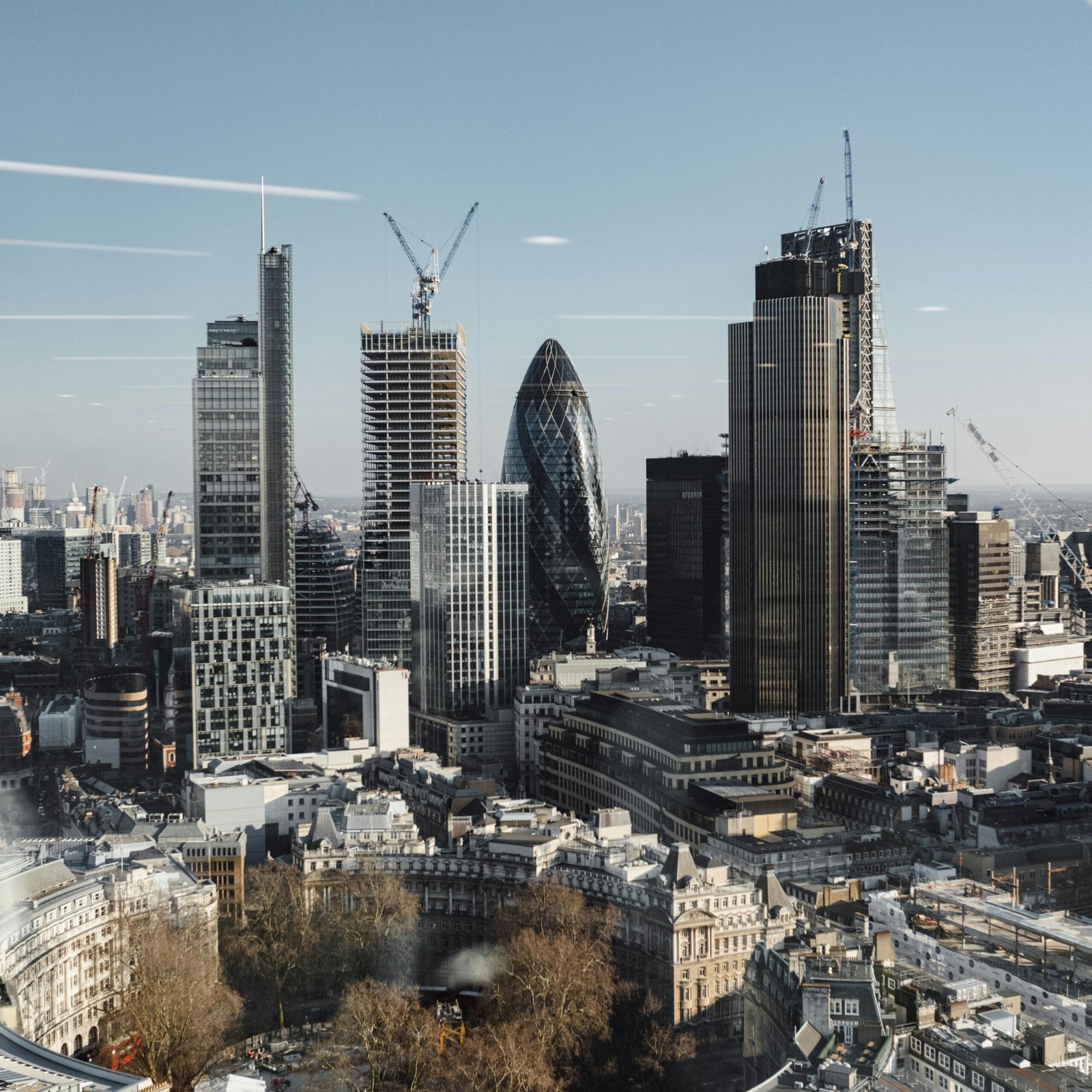 Explore London's modern skyline with iconic skyscrapers, captured from above during the day.