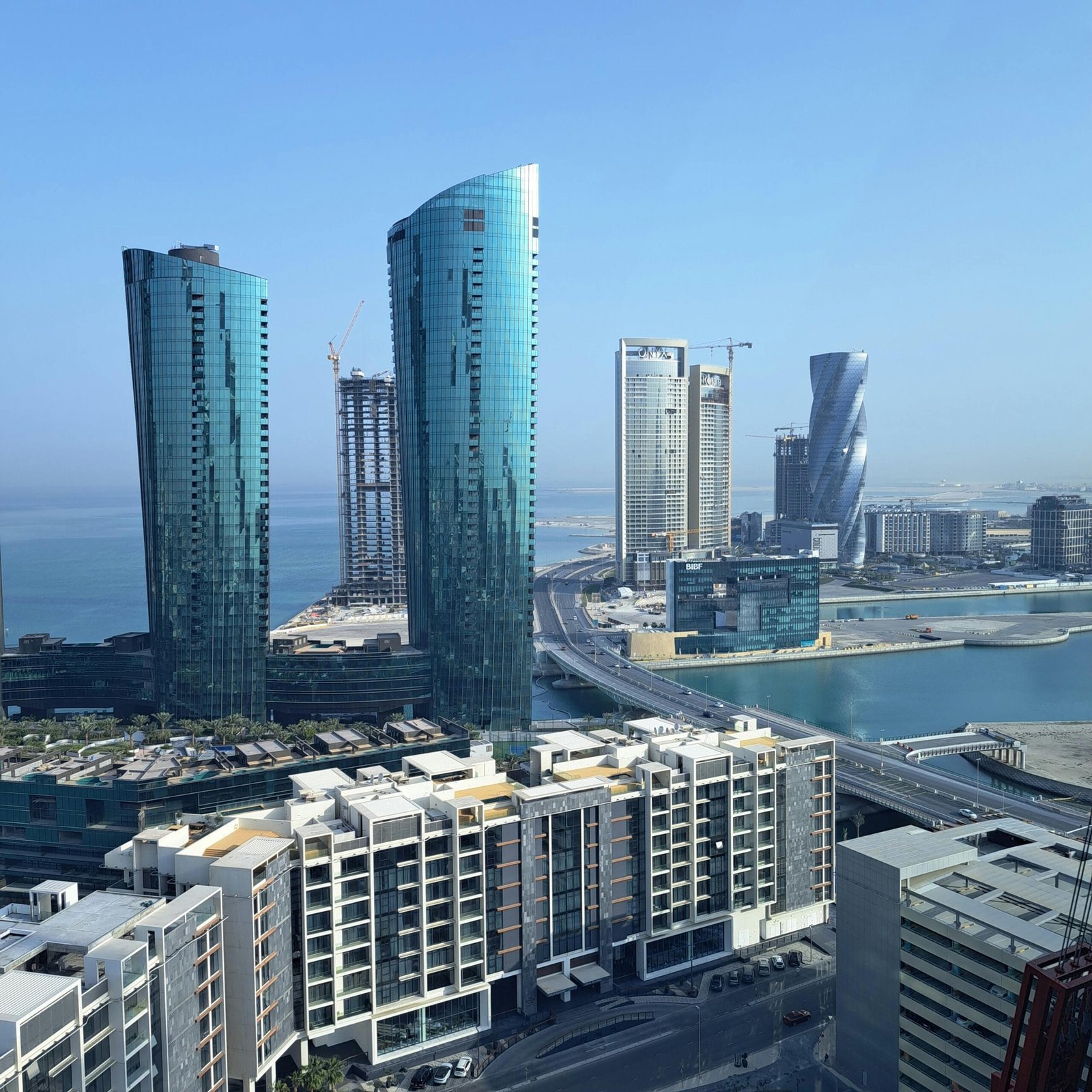 Captivating view of a modern skyline featuring waterfront skyscrapers under a clear blue sky.