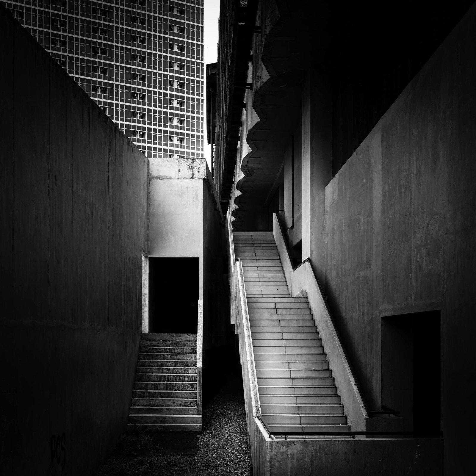 A striking black and white photograph of urban architecture showcasing angular staircases and building facades.