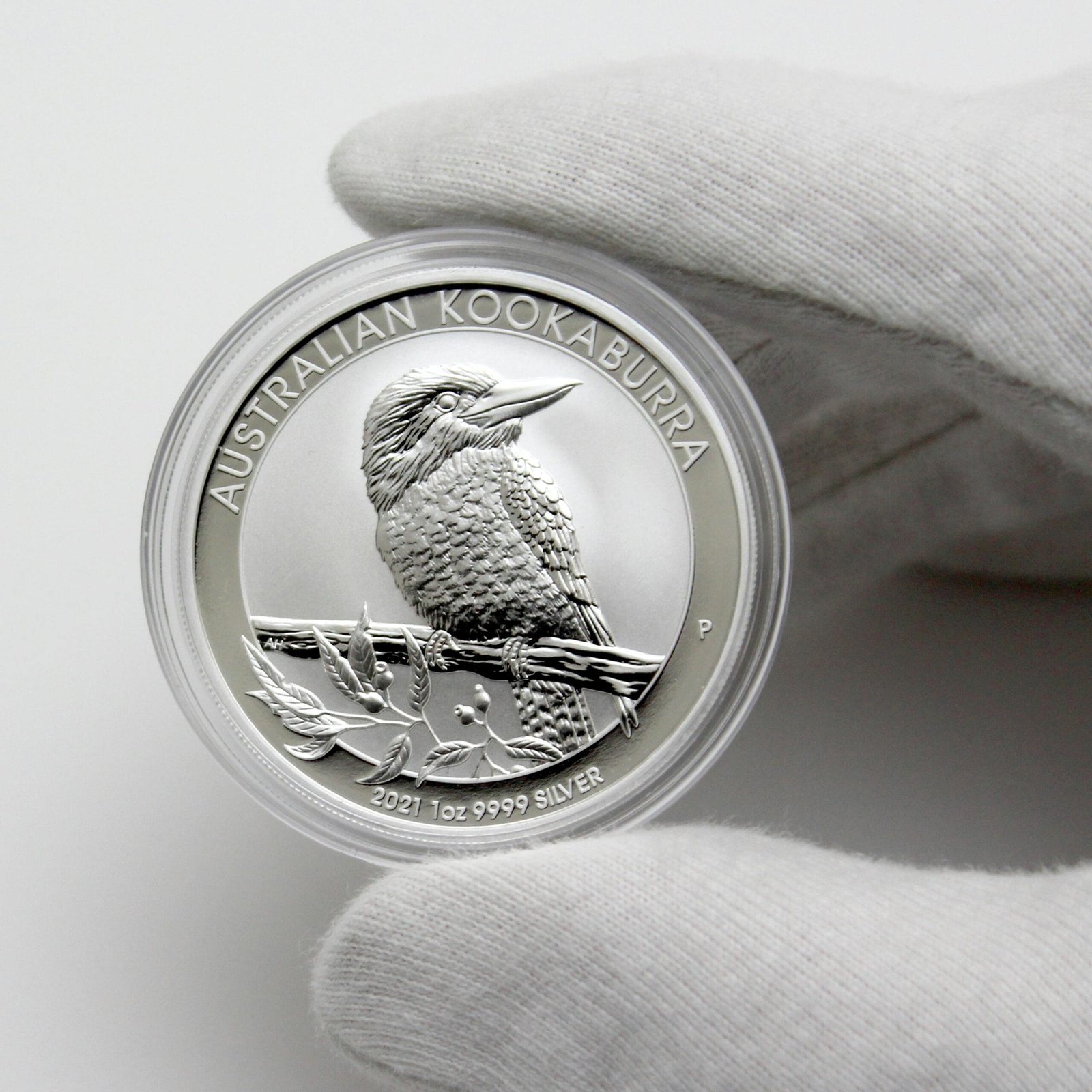 Close-up of Australian Kookaburra silver coin in a gloved hand, showcasing intricate details.