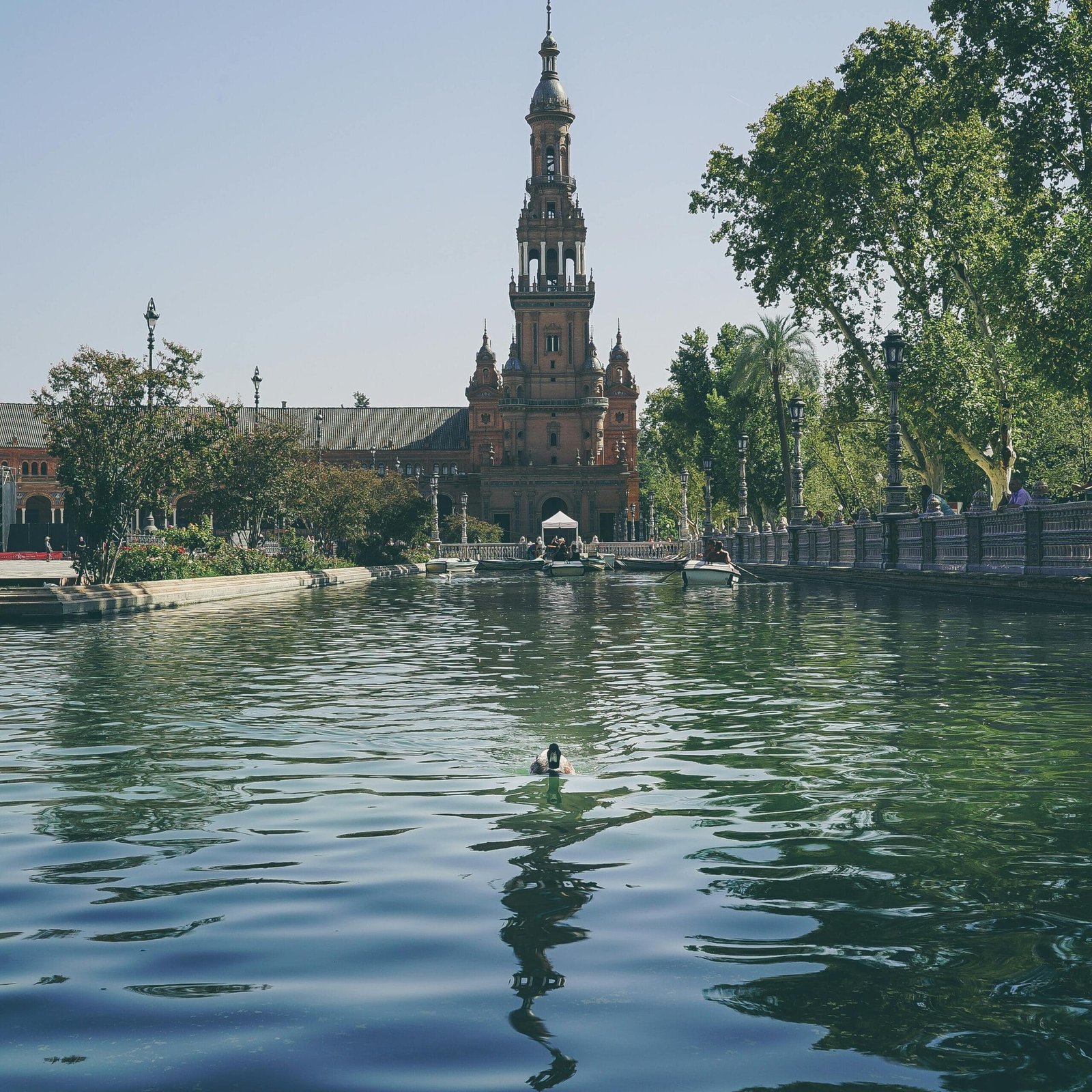 Stunning view of Plaza de España with a peaceful canal and lush greenery in Seville.