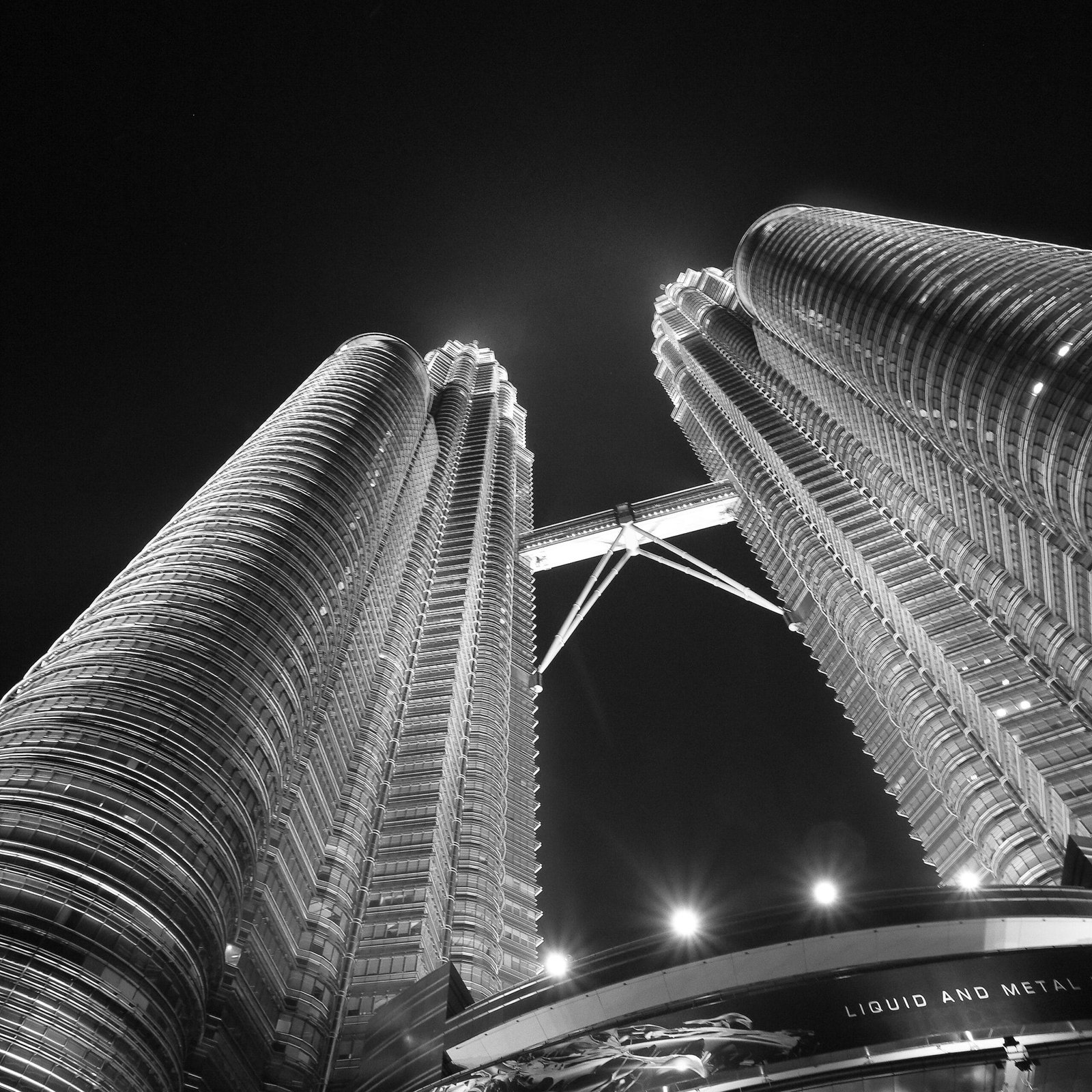 A dramatic night view of the iconic Petronas Twin Towers in Kuala Lumpur, Malaysia.