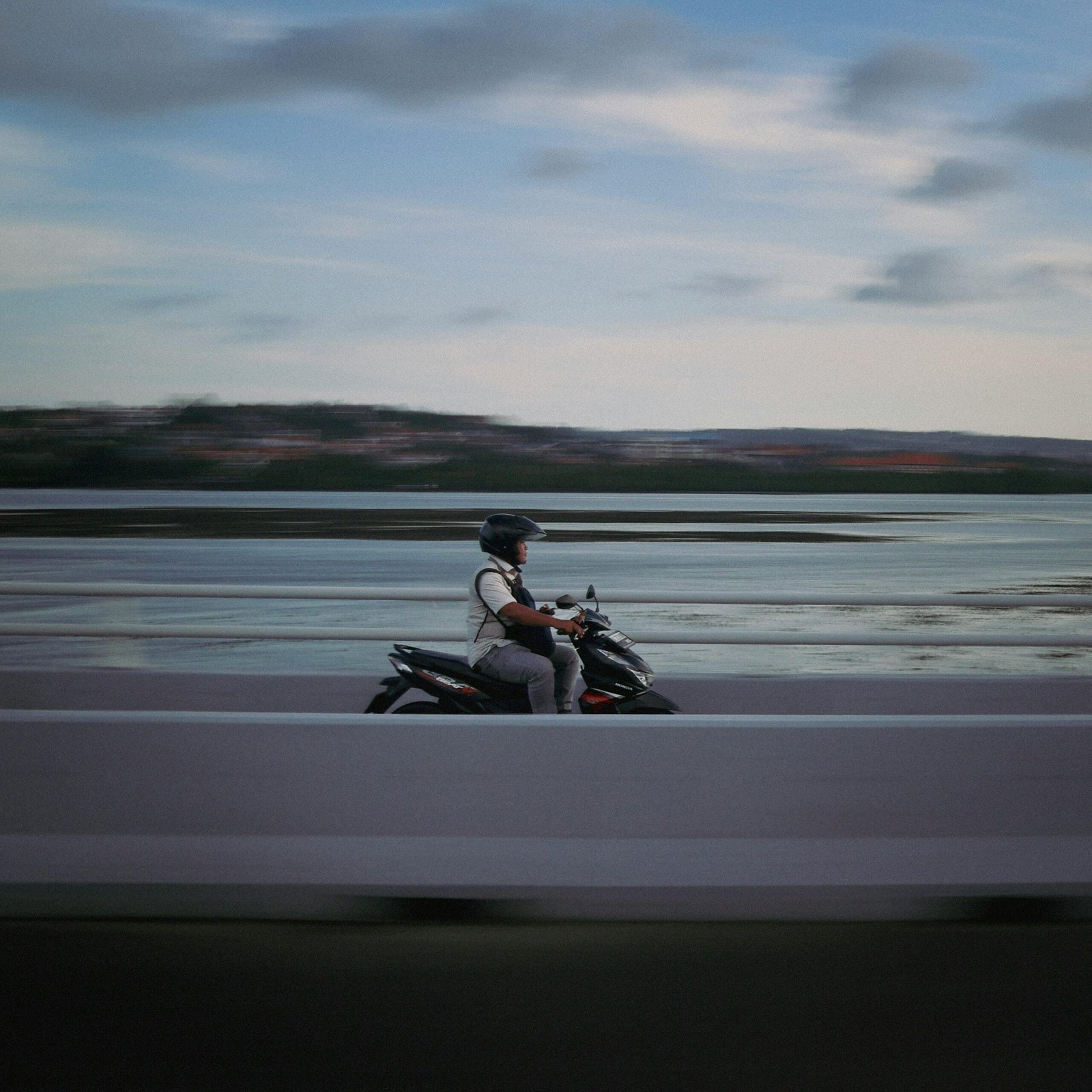 A motorcyclist rides swiftly across a bridge in Jawa Timur, Indonesia, capturing the movement and scenery.