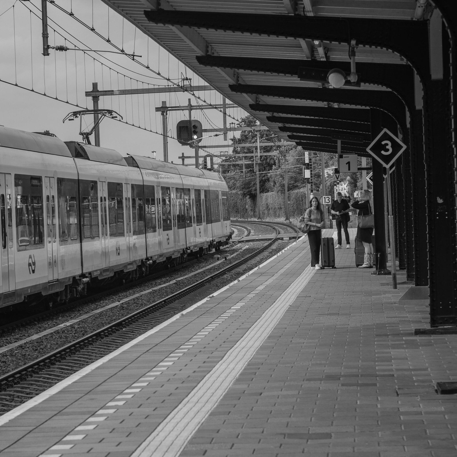 Monochrome scene of a train arriving at Bussum station in the Netherlands.
