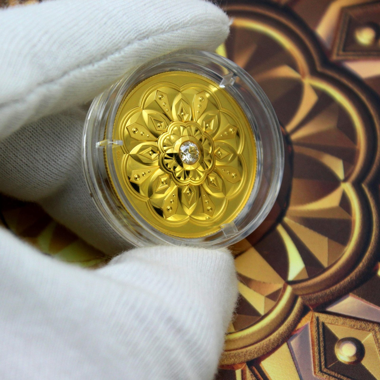 A gloved hand holds a decorative gold coin in a protective casing, showcasing intricate designs.