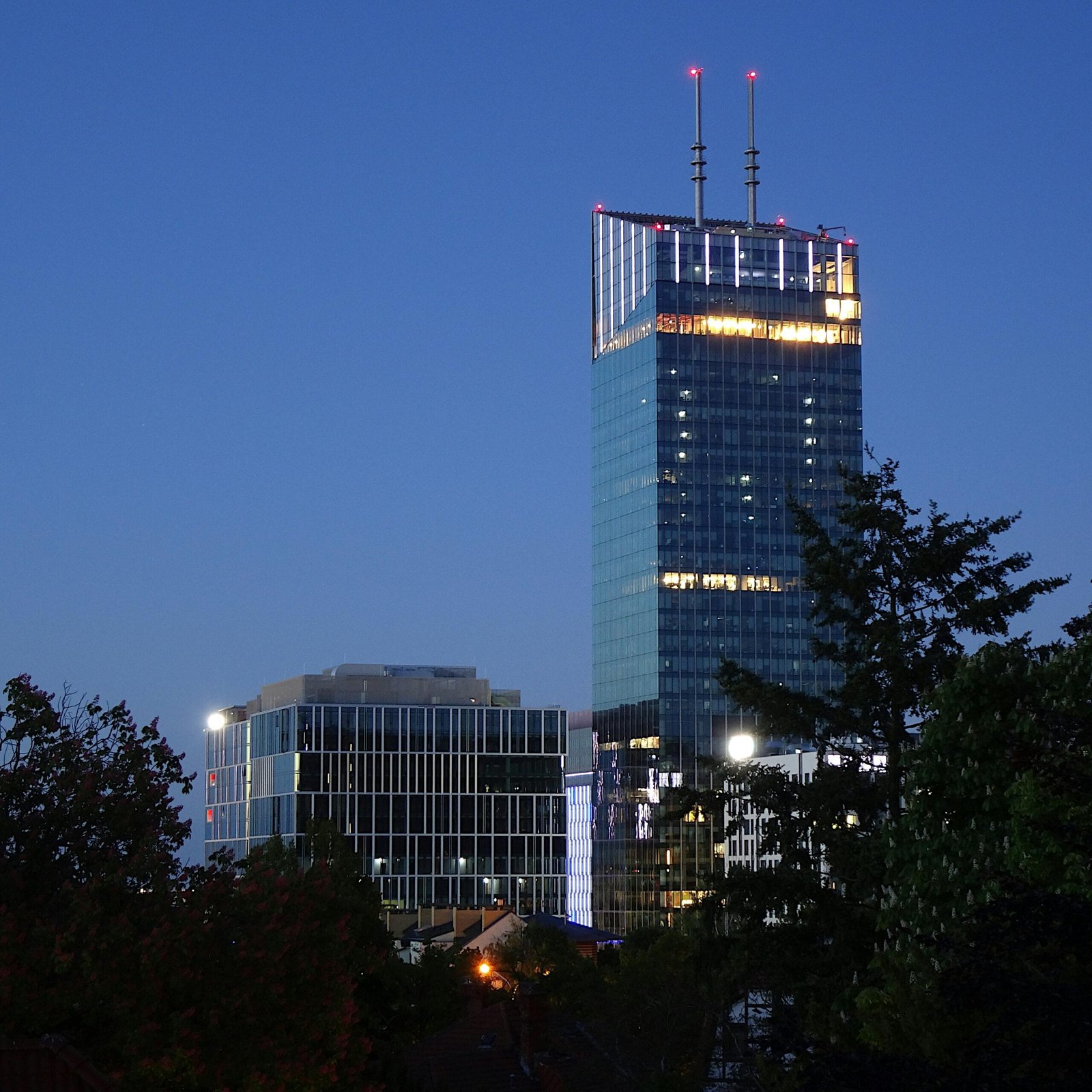 A towering skyscraper in Gdańsk, Poland, lit up against the night sky.
