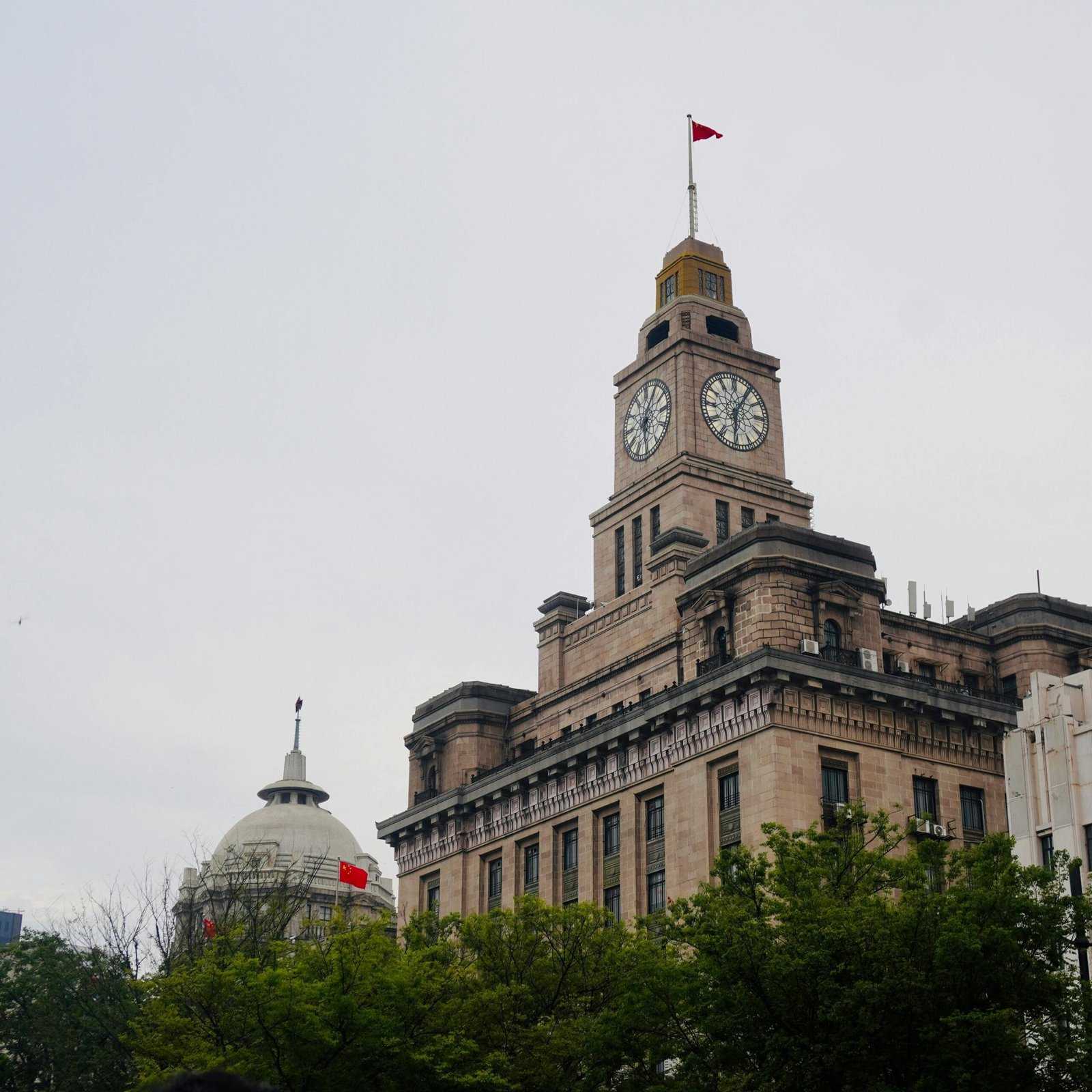Captivating view of the historic Custom House in Shanghai with clock tower and Chinese flags.