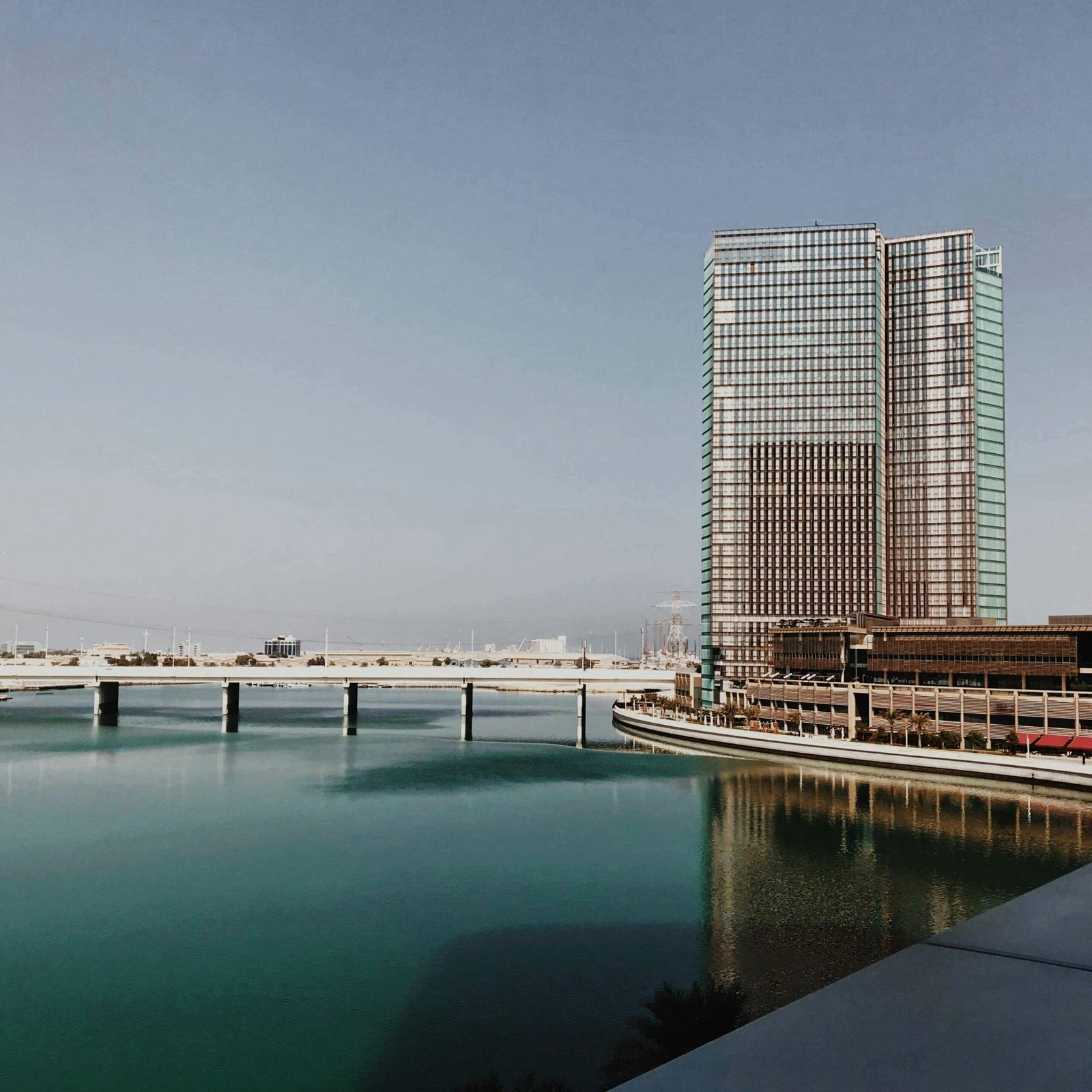 Elegant modern architecture in Abu Dhabi with clear sky reflecting on calm waters.