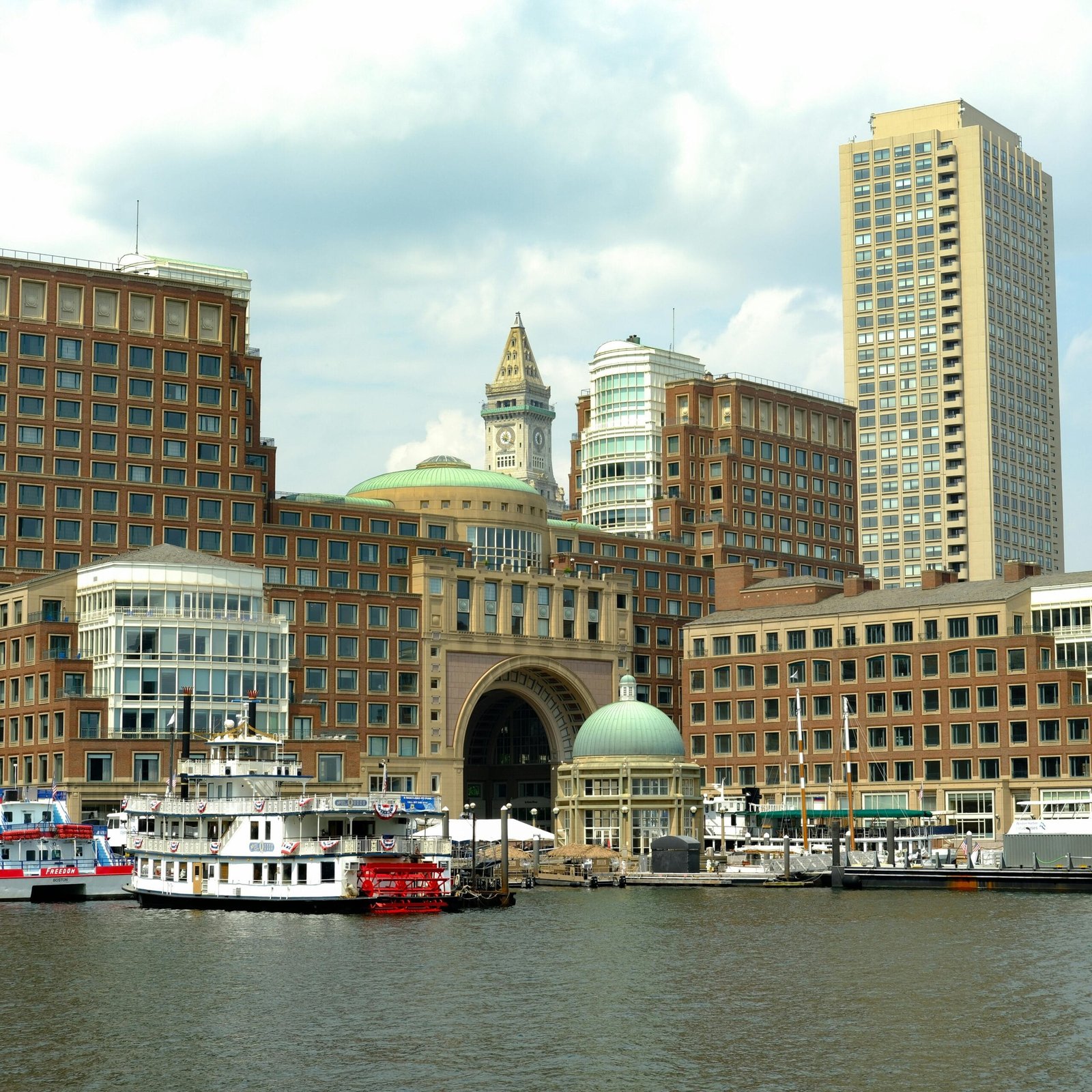Historic Boston Harbor with boats and iconic skyline showcasing urban architecture.