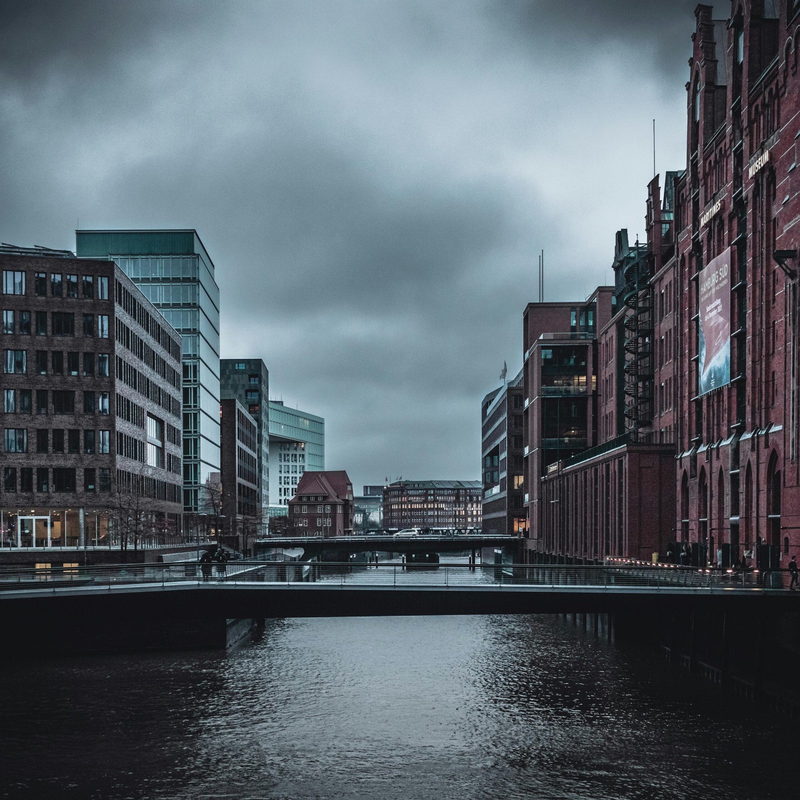 A moody urban scene with a canal and buildings under a gloomy sky in Hamburg, Germany.