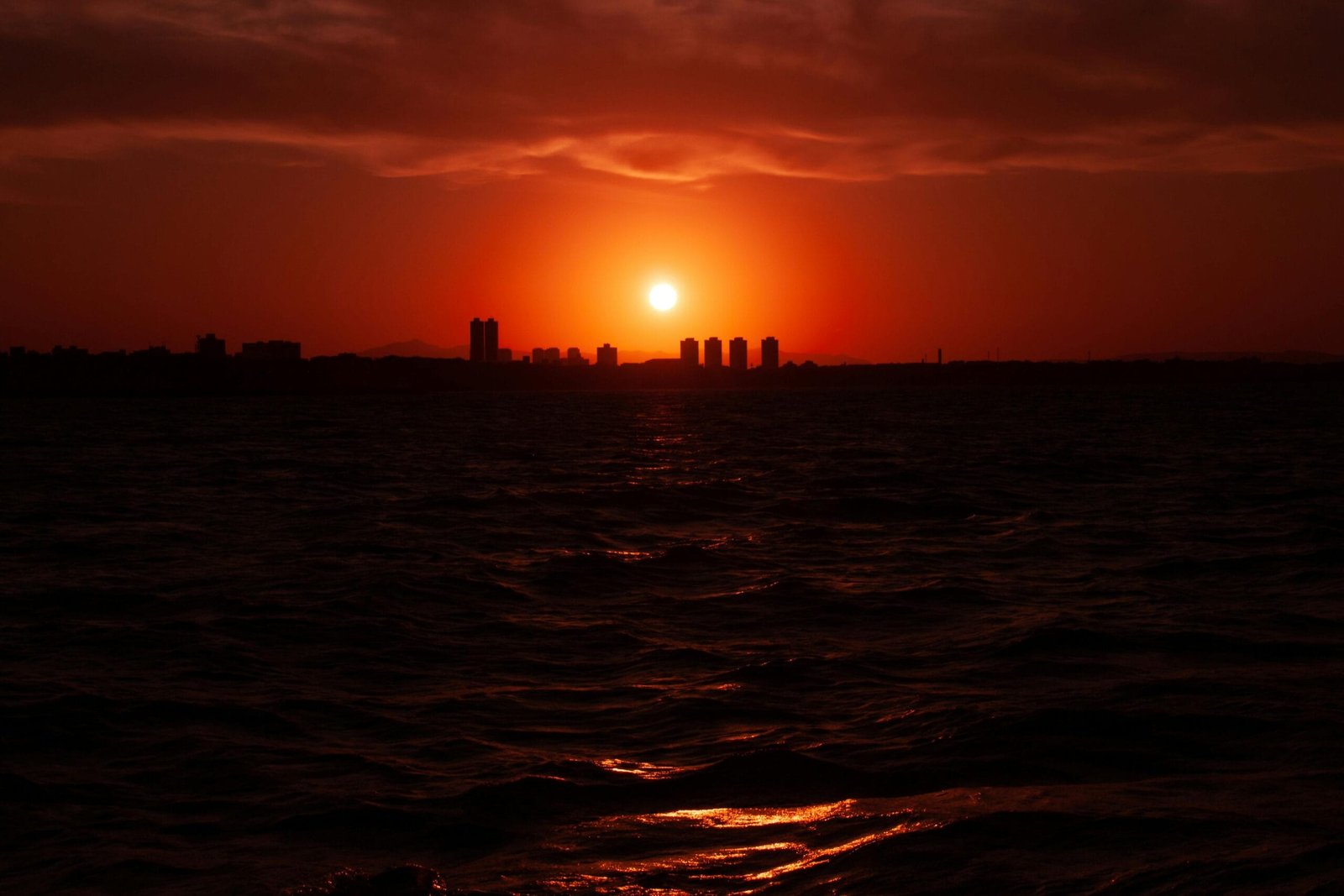 Captivating sunset with a red sky over Fortaleza skyline and sea.