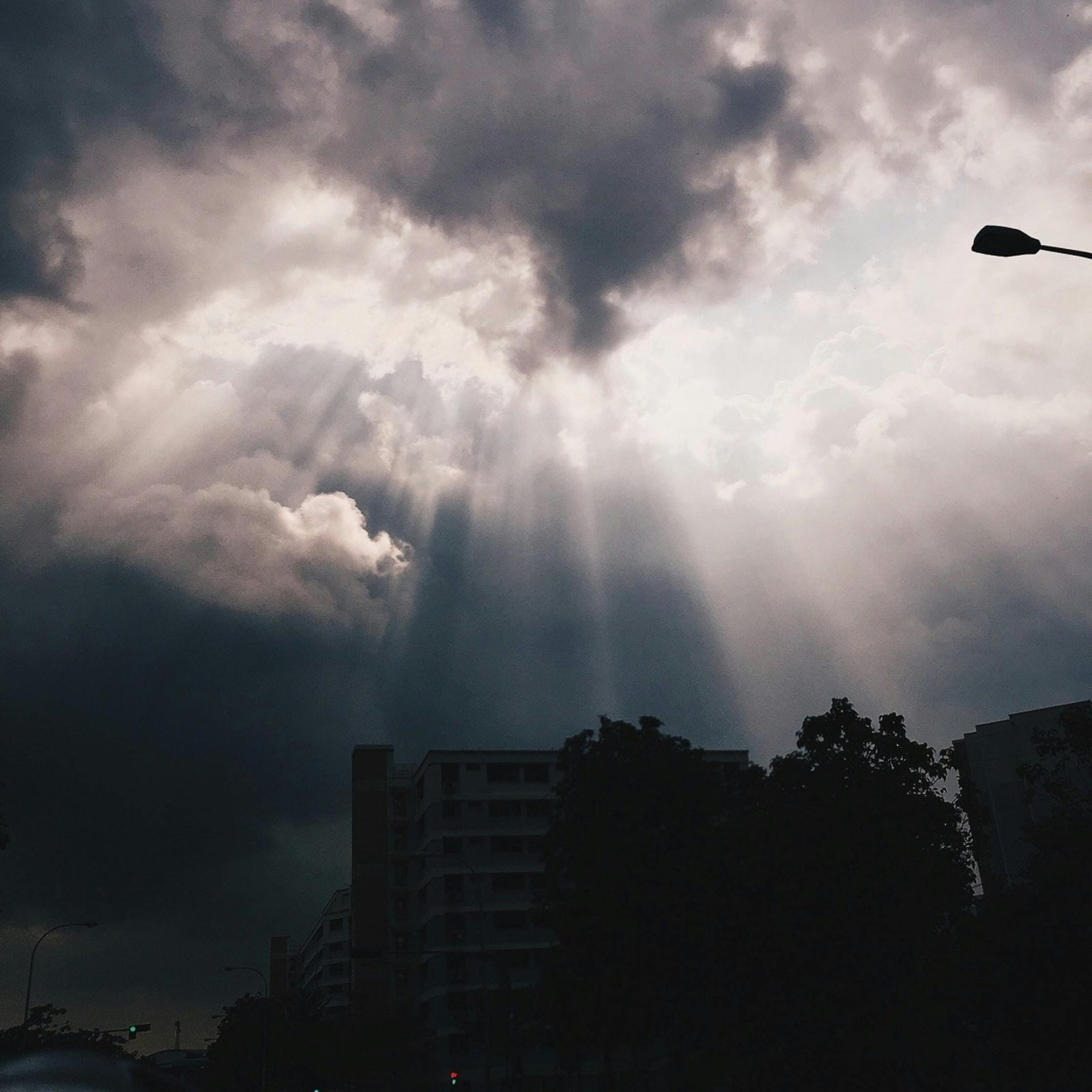Breathtaking view of sun rays piercing through clouds over Singapore urban scene.