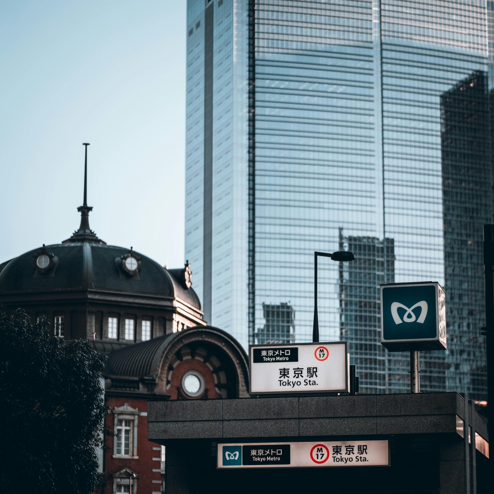 View of Tokyo Station with a modern skyscraper in the background, embodying urban contrast.