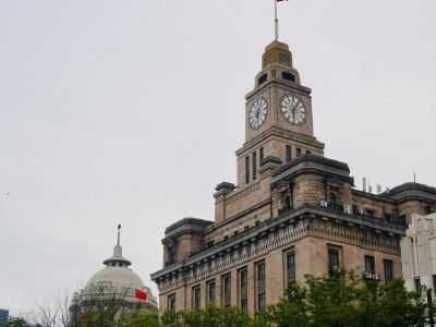 Captivating view of the historic Custom House in Shanghai with clock tower and Chinese flags.