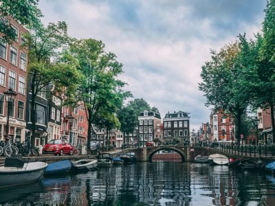 Charming view of an Amsterdam canal lined with bicycles, boats, and historic buildings.