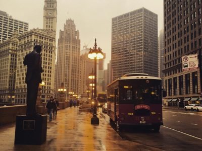 A rainy day scene in downtown Chicago featuring urban architecture, a bus, and the city skyline.