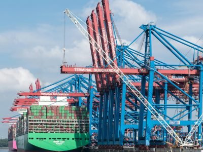 Cranes and container ships at Terminal Burchardkai in Hamburg port on a clear day.