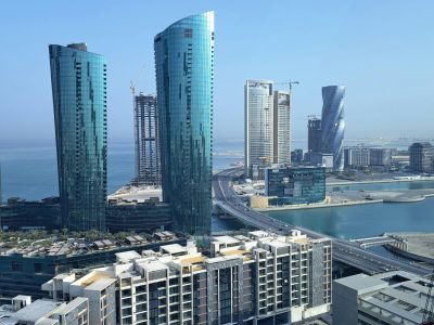 Captivating view of a modern skyline featuring waterfront skyscrapers under a clear blue sky.