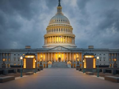 Stunning view of the illuminated United States Capitol building against dramatic clouds in Washington, DC at dusk.