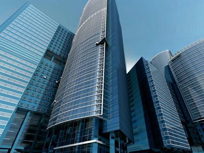 Futuristic urban skyscrapers with glass facades reflecting a vibrant blue sky.