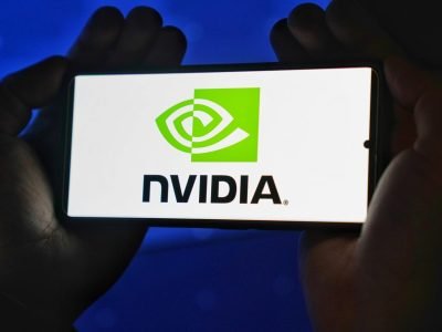 Hands holding a smartphone showing the NVIDIA logo on a bright screen.