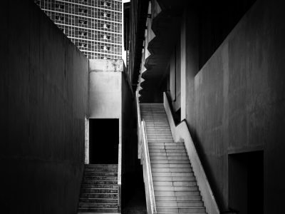 A striking black and white photograph of urban architecture showcasing angular staircases and building facades.