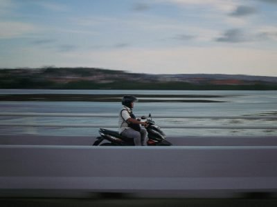 A motorcyclist rides swiftly across a bridge in Jawa Timur, Indonesia, capturing the movement and scenery.