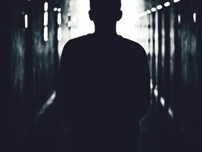 Silhouette of a person standing in a shadowy tunnel, evoking mystery.