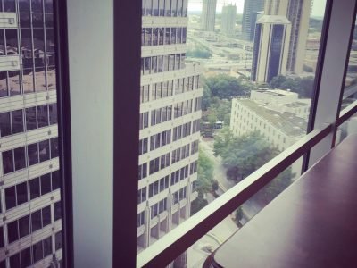 Window view of modern city skyline and skyscrapers from a high-rise office.
