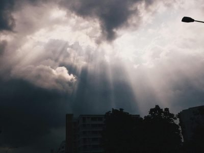 Breathtaking view of sun rays piercing through clouds over Singapore urban scene.