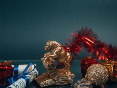 A golden bull figurine with festive decorations, coins, and gifts symbolizing prosperity for the New Year.