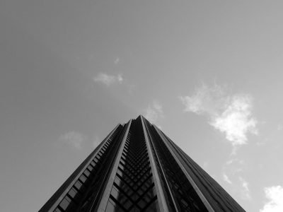 From above of black and white contemporary skyscraper with geometric facade under cloudless sky in sunlight