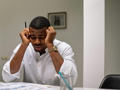 A worried businessman in corporate attire handling stress at his workspace.